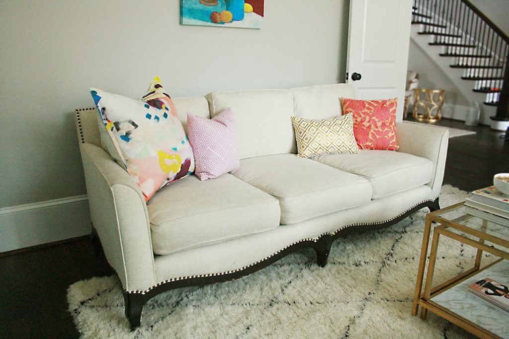 reupholstered white sofa with colorful pillows and shag rug