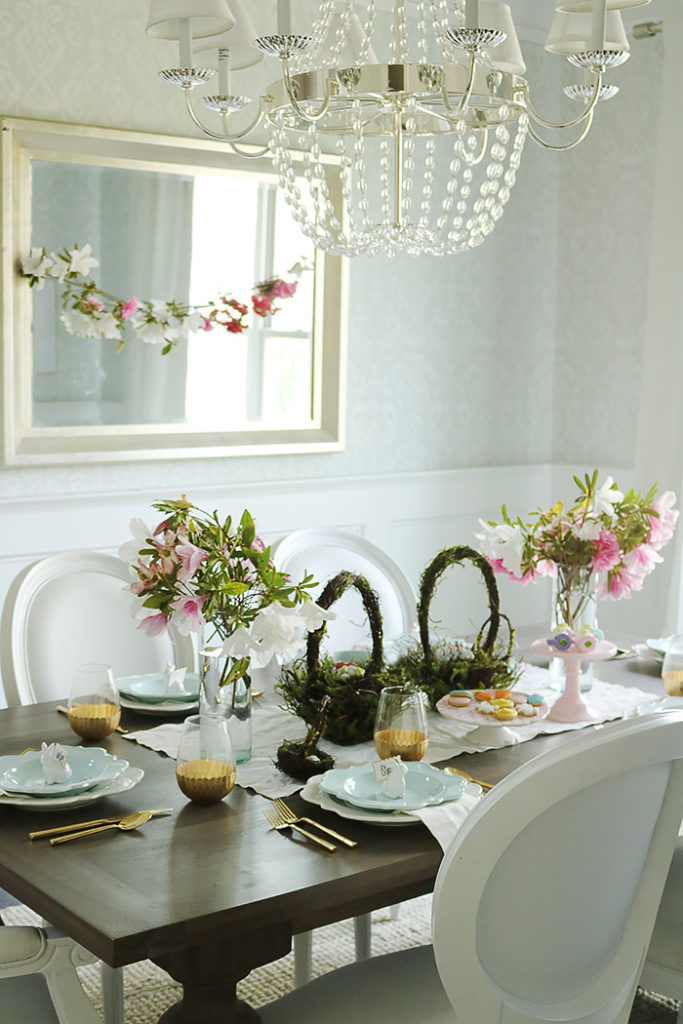 easter tablescape using flower branches, easter table decorations, floral centerpieces, flower branches centerpieces, natural, simple easter tables, flower garland, moss basket, easter eggs, bunny place setting, blue plates, scallop plates