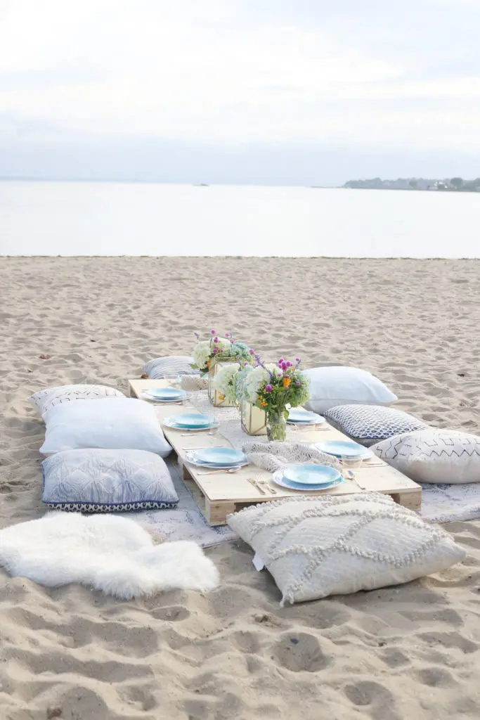 Boho Birthday Beach dinner with pillows and vintage rugs.  Set up plates and table decor on pallet and add pillows.  Birthday Beach dinner idea, beach dinner casual || Darling Darleen