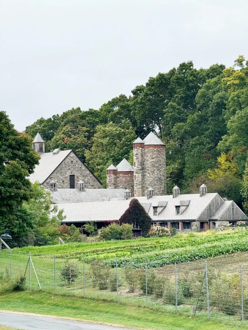 Your Guide to the Best Fall Activities Near Fairfield County, Connecticut in the month of October from pumpkin patches to haunted houses! A stone farmhouse with three silos and a pitched roof, surrounded by trees and a garden, enclosed by a chain-link fence.